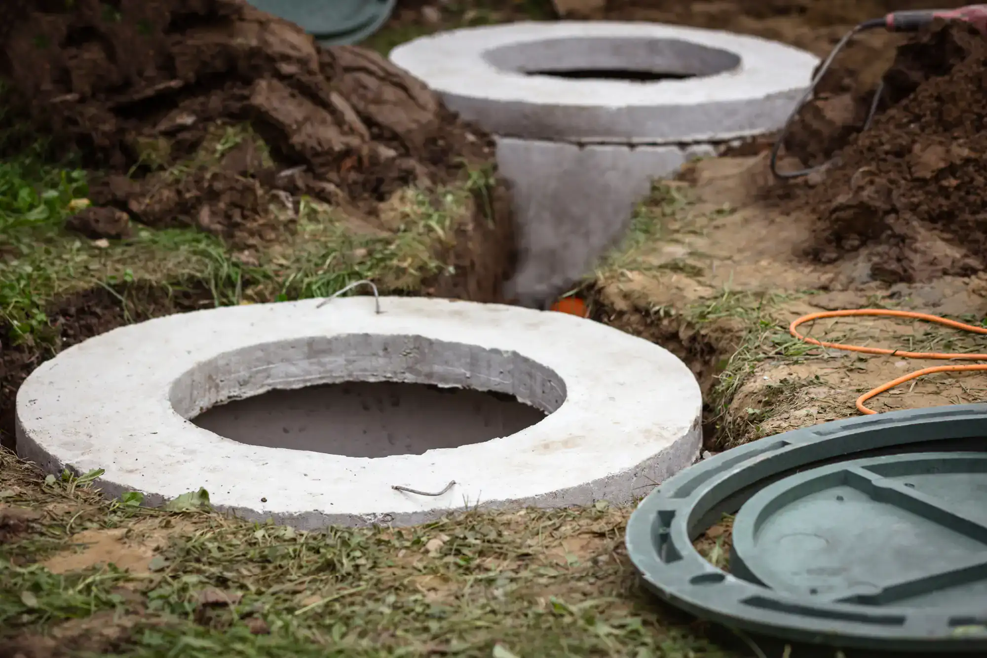 Two open concrete septic tank lids with green covers nearby&mdash;Cesspool Service Suffolk County available.