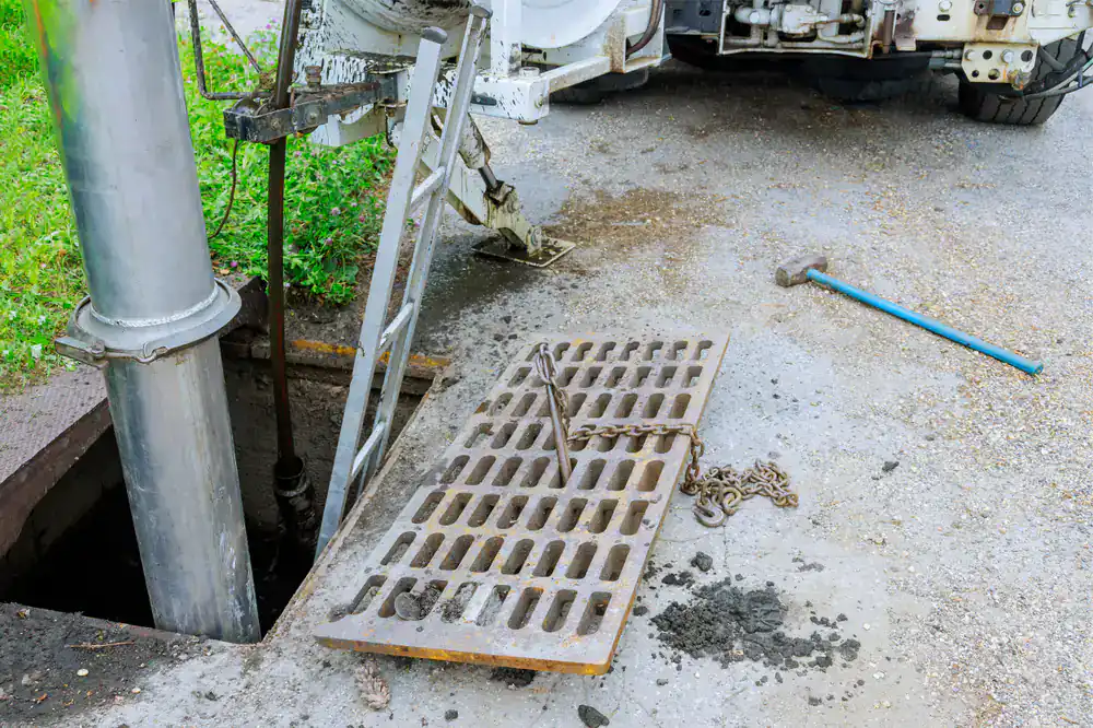 Open manhole with removed grate, ladder, and vacuum hose&mdash;tools ready for drain cleaning in Suffolk County.