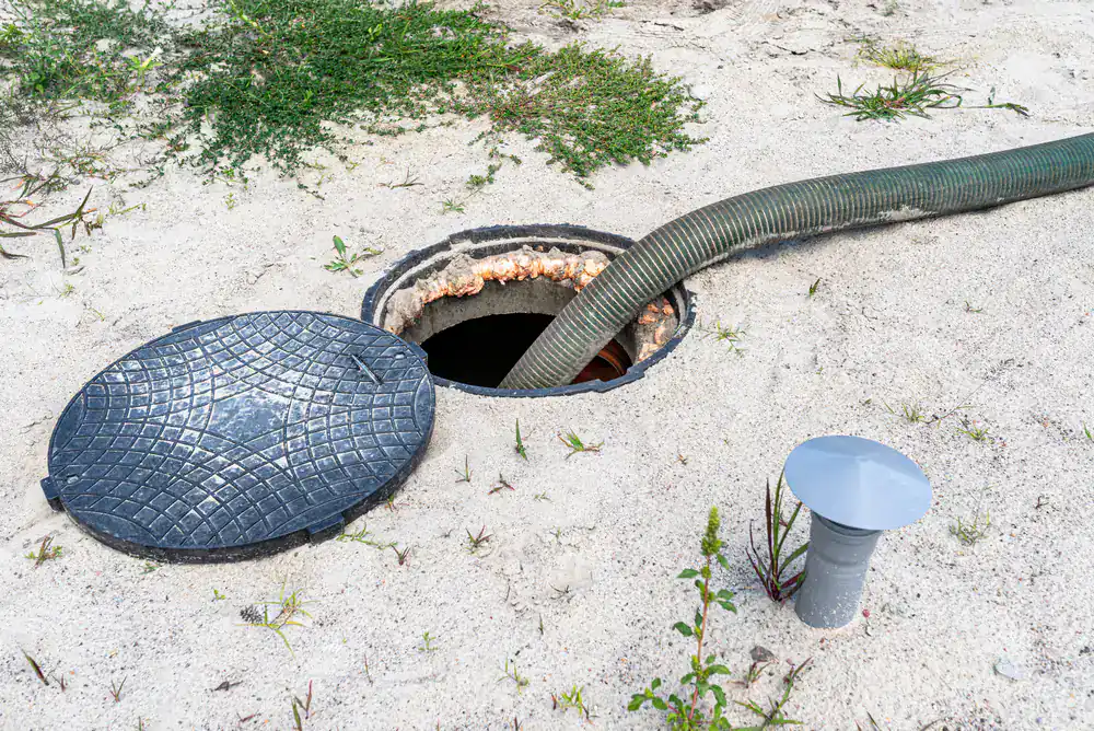 A septic tank in NY is being serviced by Septic Services Suffolk County, with its lid open and hose attached.