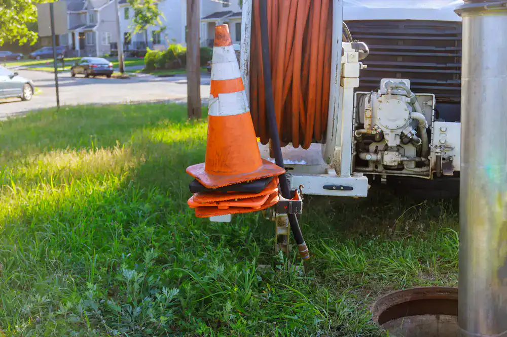 Four orange traffic cones and a utility vehicle near an open manhole in Suffolk County.