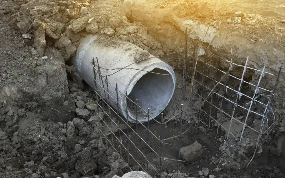 A concrete drainage pipe lies in dirt at a construction site, suitable for drain cleaning Suffolk County.